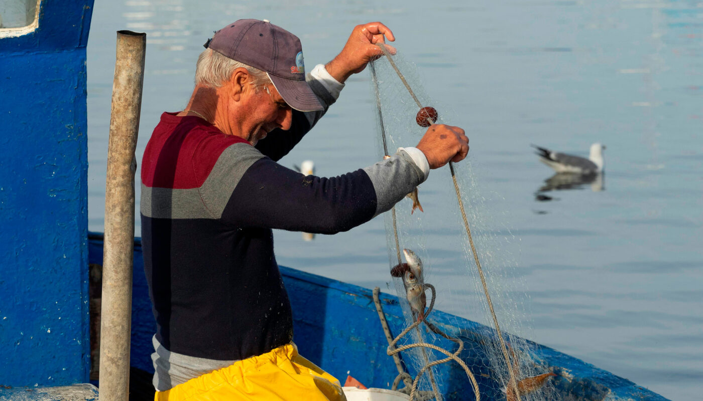 Somos-productores Imagen de hombre recogiendo una red de pesca en un barco